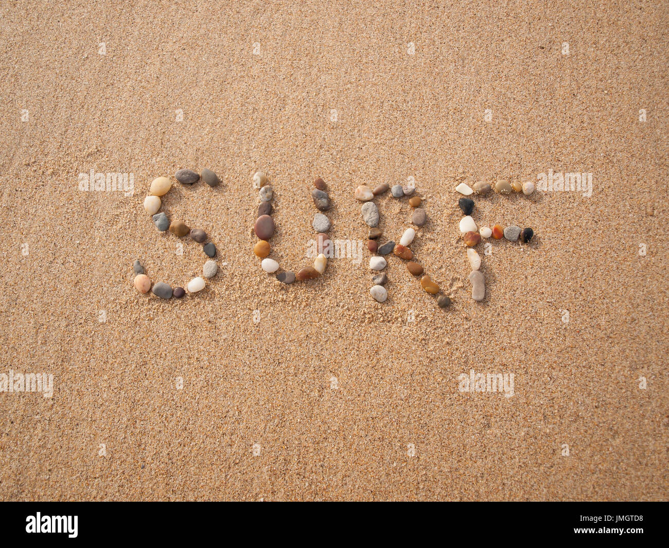 Palabra escrita de surf con piedras y conchas en la playa por el océano Foto de stock