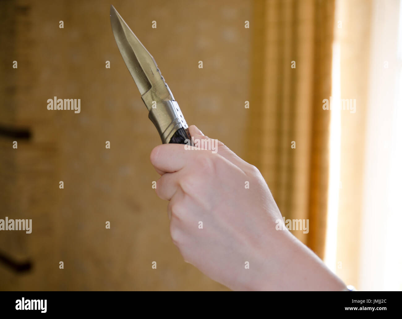 Concepto de robo o crimen de cuchilla con la mano sujeta la cuchilla dentro de casa Foto de stock