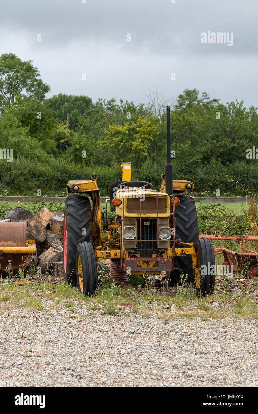 Viejo tractor amarillo sobre residuos de tierra. Foto de stock