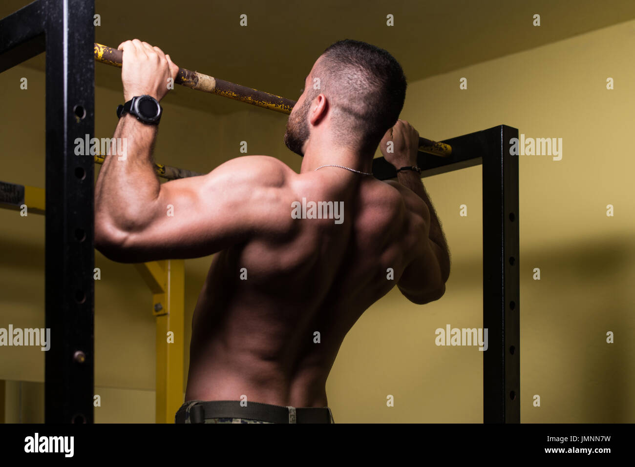 Hombre deportista haciendo tirar ups - Chin-Ups en el gimnasio. Foto de stock