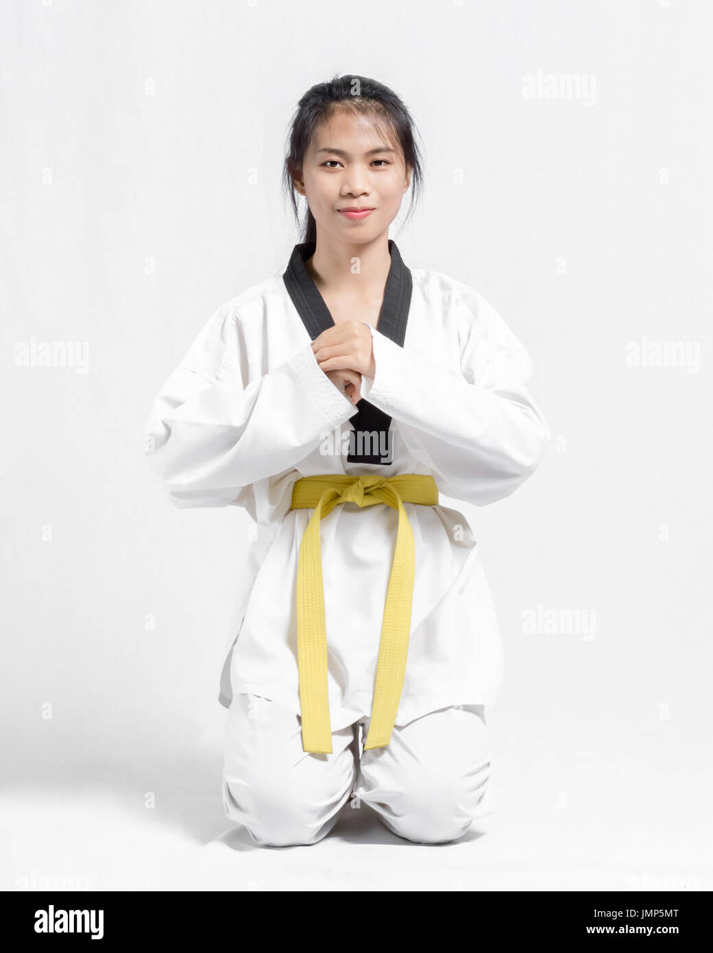 Retrato de una preciosa mujer asiática con el taekwondo cinturón amarillo.  Aislado sobre fondo gris Fotografía de stock - Alamy