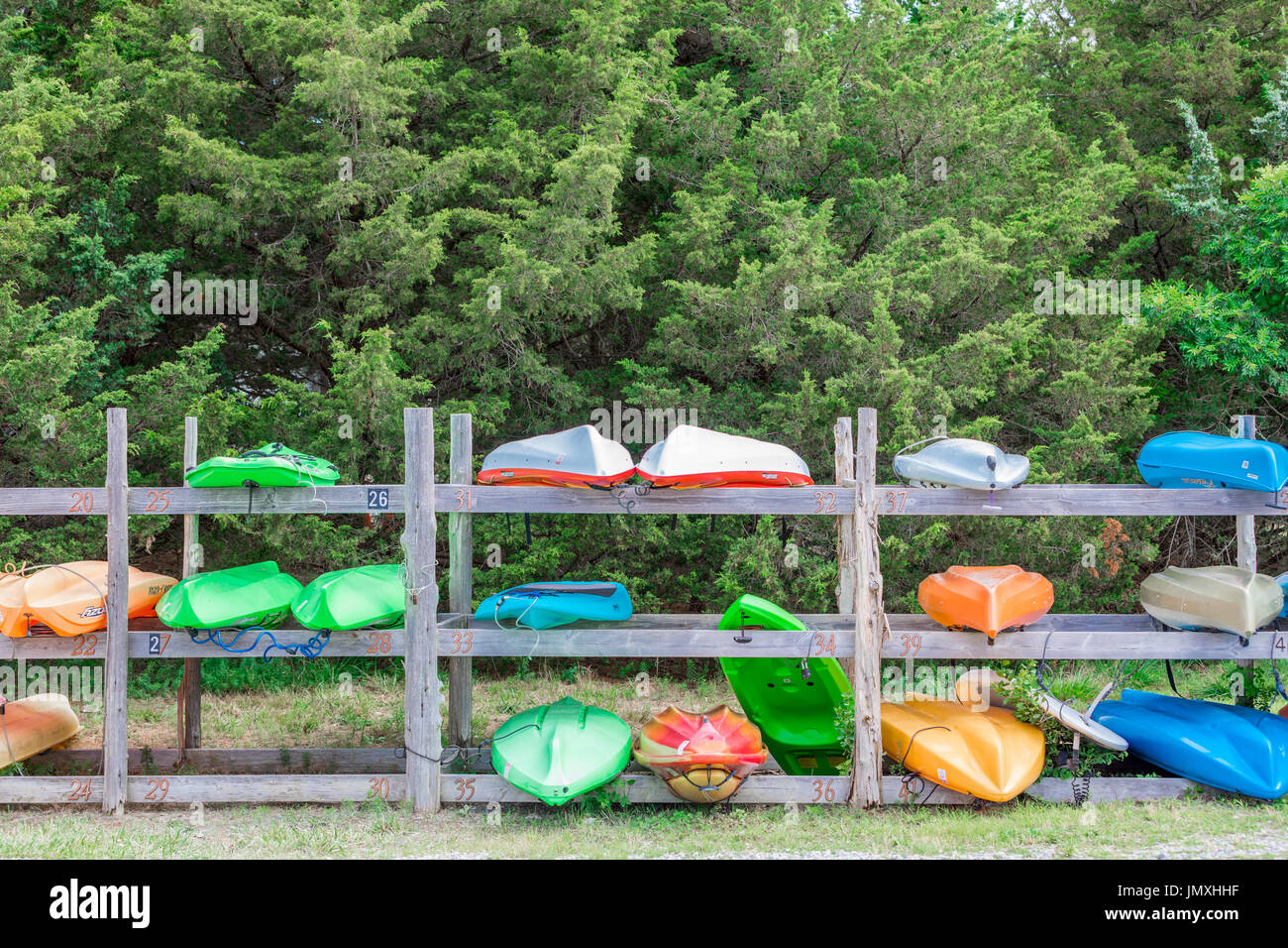 Varios colores de kayaks en un estante de madera en el agua clara en la playa de East Hampton, NY Foto de stock