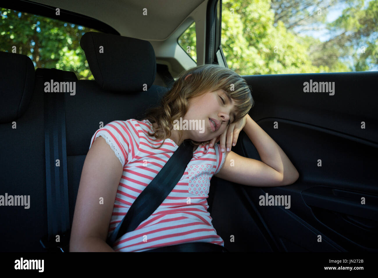 Lindo adolescente durmiendo en el asiento trasero del coche Foto de stock