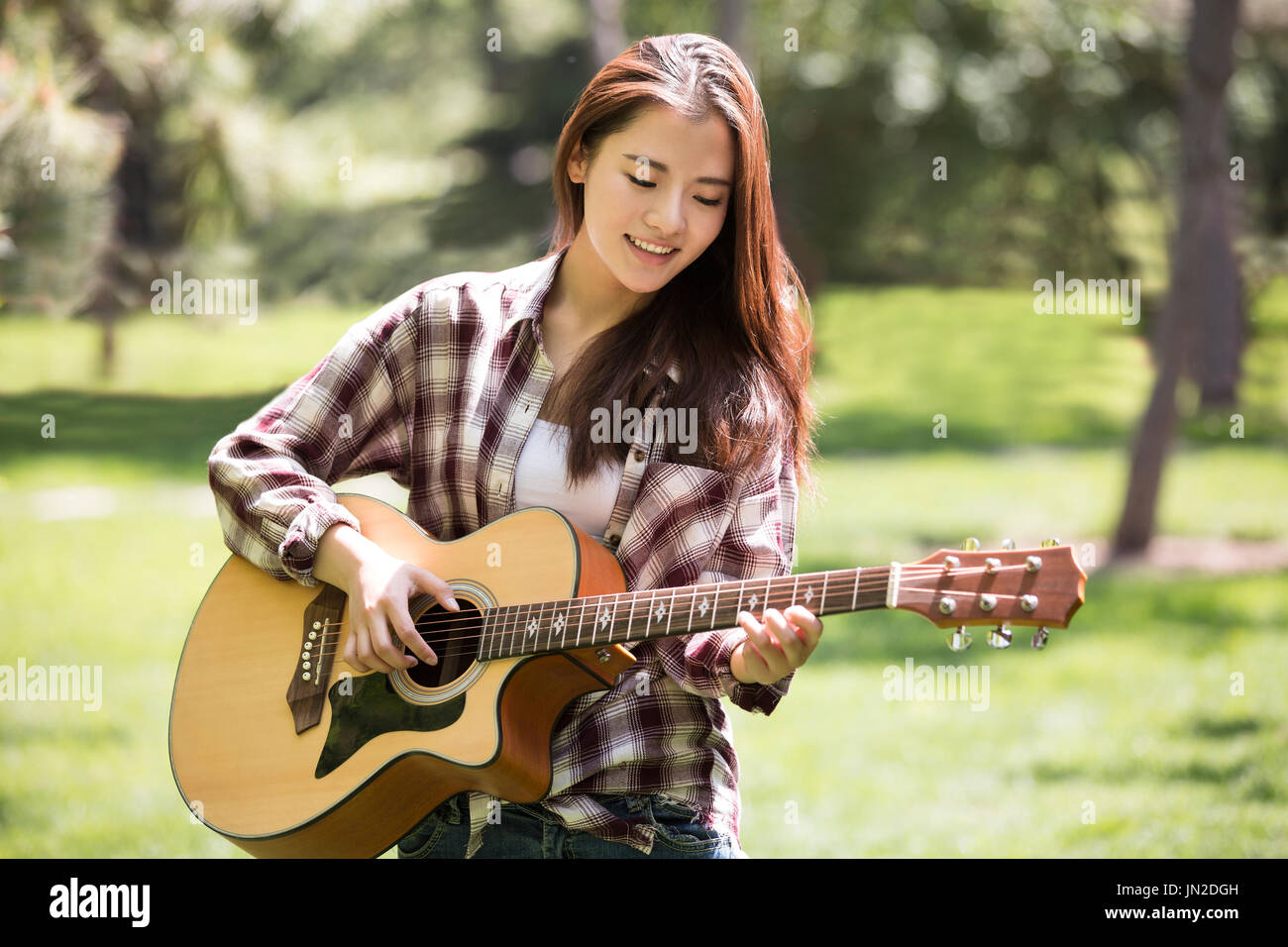 Las mujeres jóvenes tocando la guitarra en el césped Foto de stock