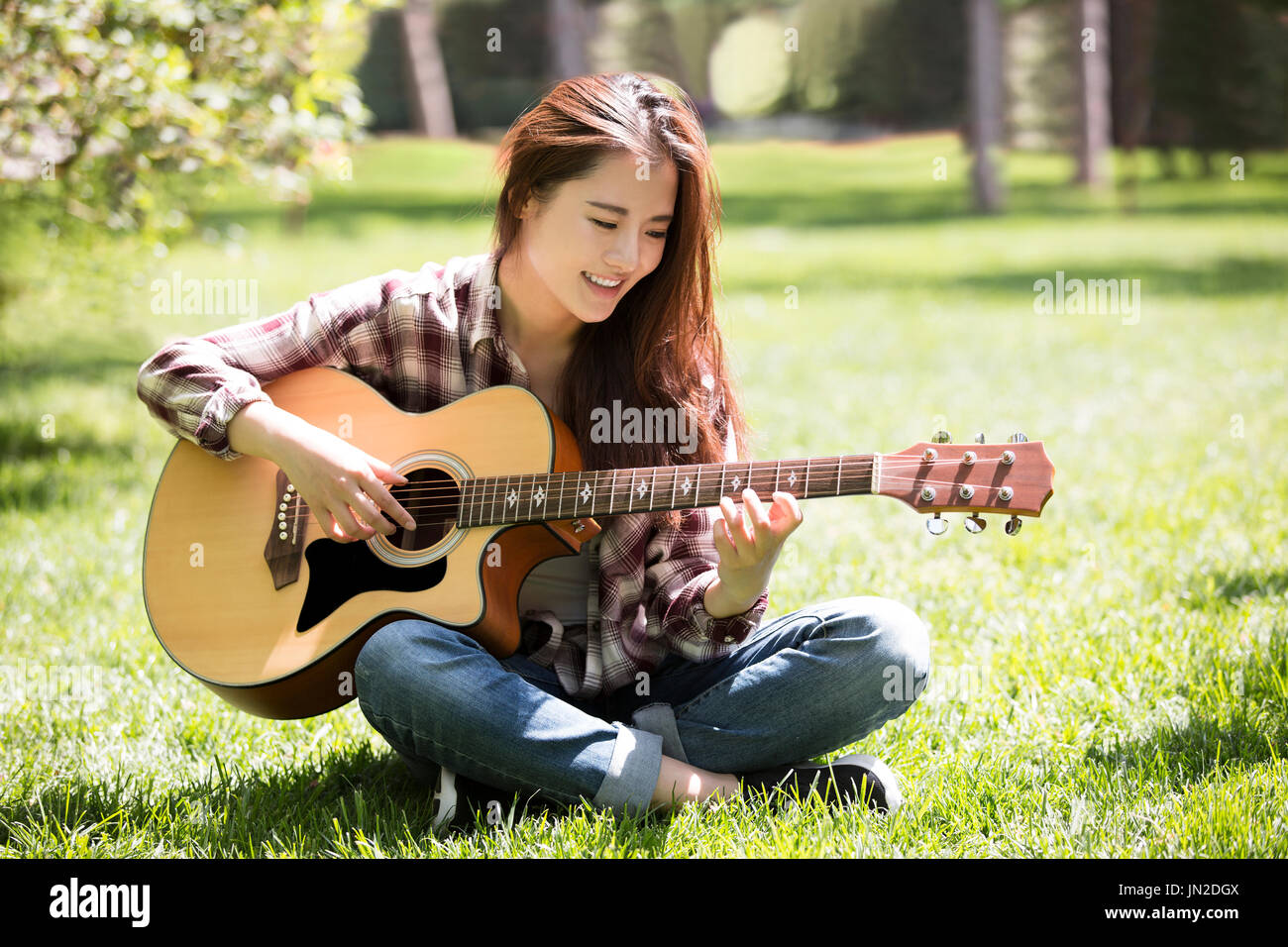 Las mujeres jóvenes tocando la guitarra en el césped Foto de stock