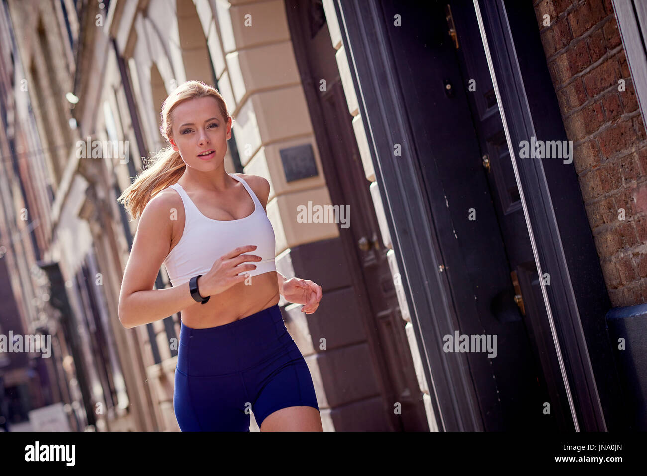 Mujer joven corriendo en entorno urbano Foto de stock