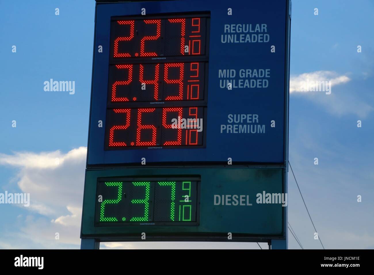 Los precios del gas de neón rojo y verde contra el cielo nublado cerca del atardecer Foto de stock