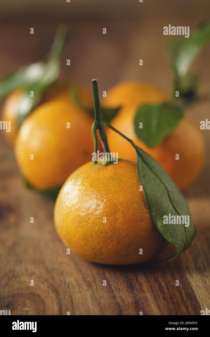 Mandarinas orgánico con hojas en tabla de madera Foto de stock