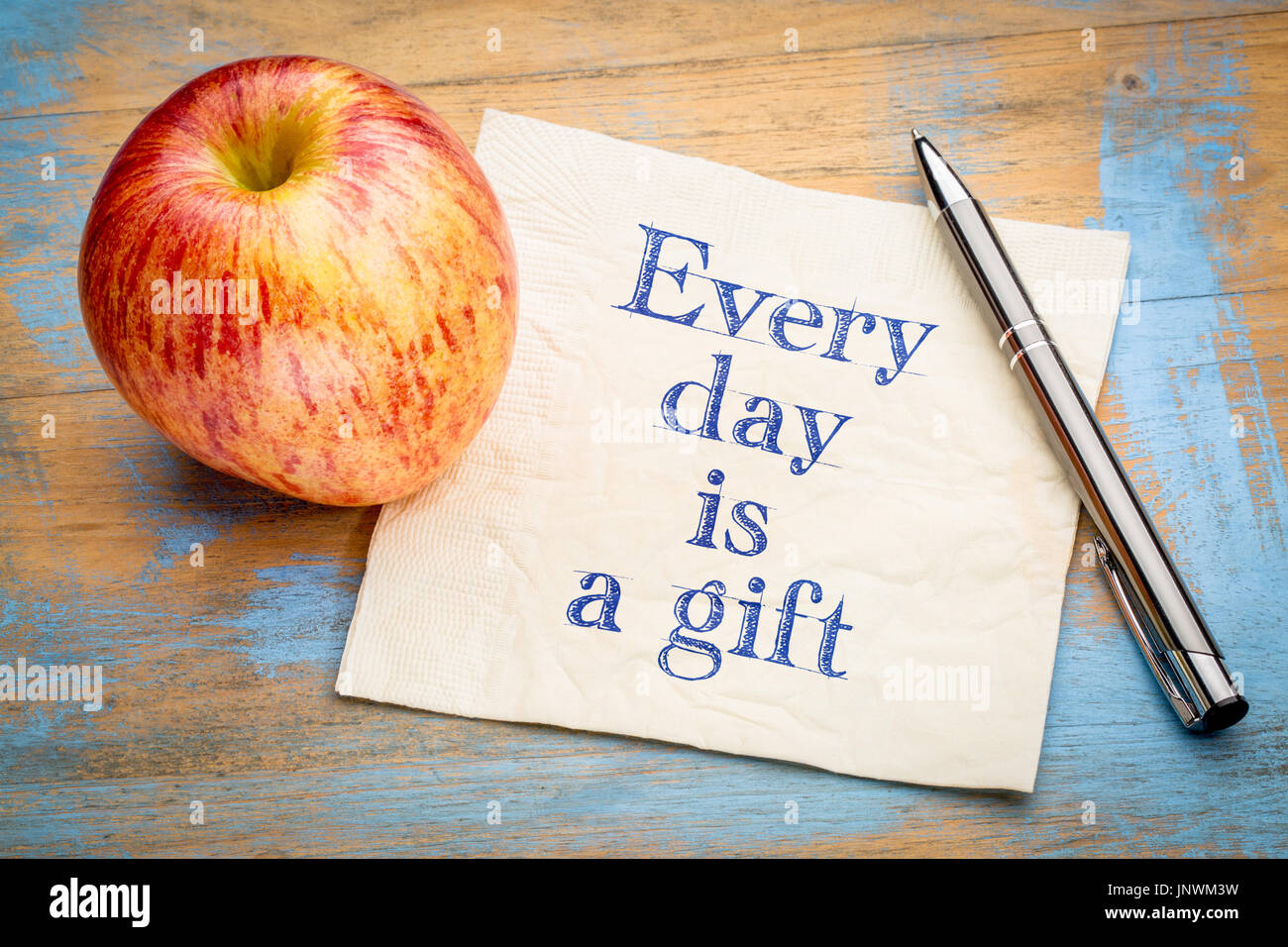 Cada día es un regalo recordatorio - inspirador de la escritura a mano en una servilleta con una manzana fresca Foto de stock