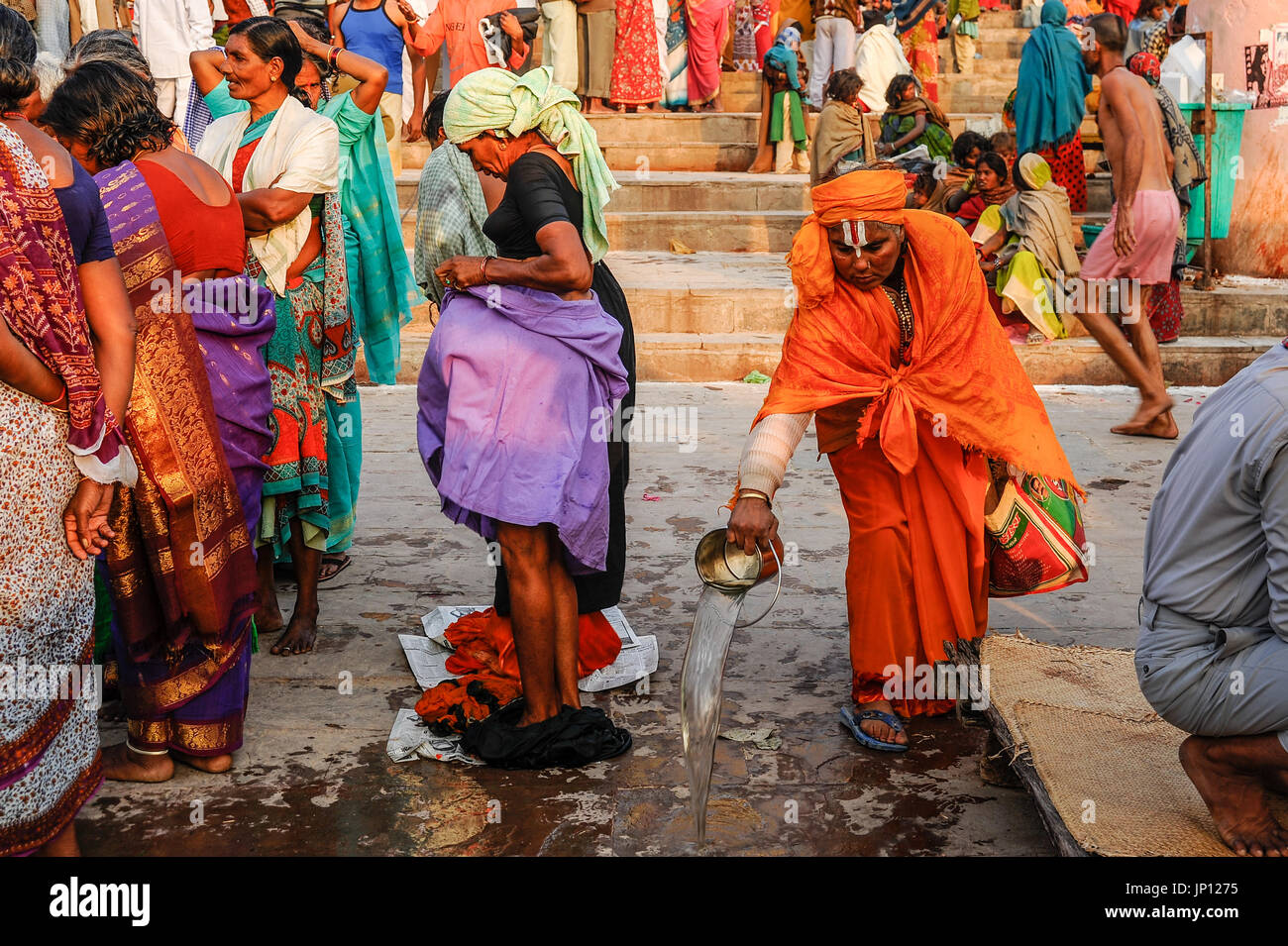 Una Sadhvi (hembra sadhu) vierte agua en el sagrado Ganges en Varanasi Ghats Foto de stock