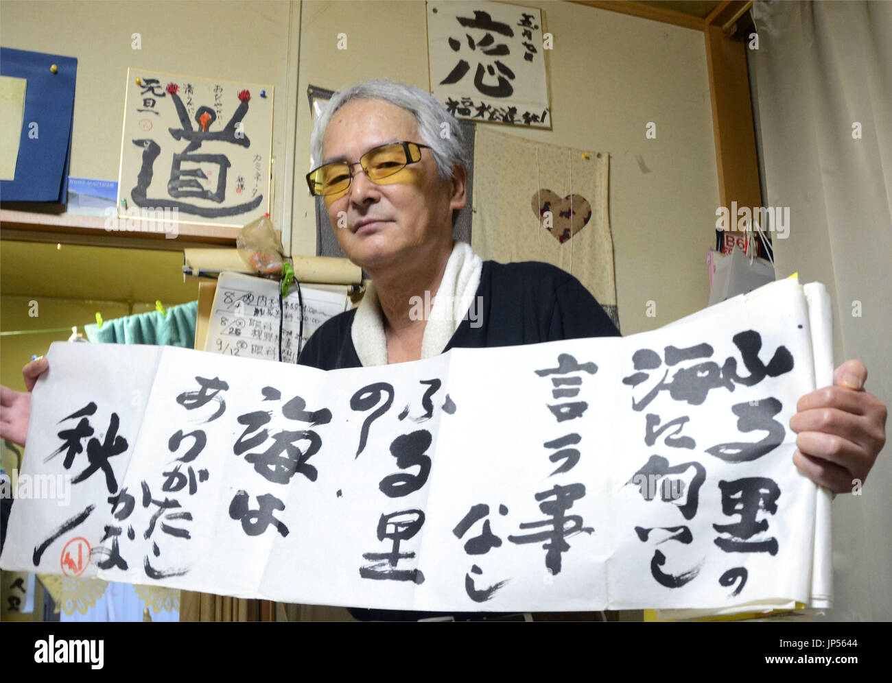 MORIOKA, Japón - Shuetsu Kubo, que tiene la debilidad de la vista, contiene una muestra de su caligrafía en Kamaishi, Prefectura de Iwate, noreste de Japón, el 26 de agosto, 2014. Kubo comenzaron a expresar su gratitud por su familia a través de la caligrafía tras perder a su hermano menor en el 2011 terremoto y maremoto. (Kyodo) Foto de stock