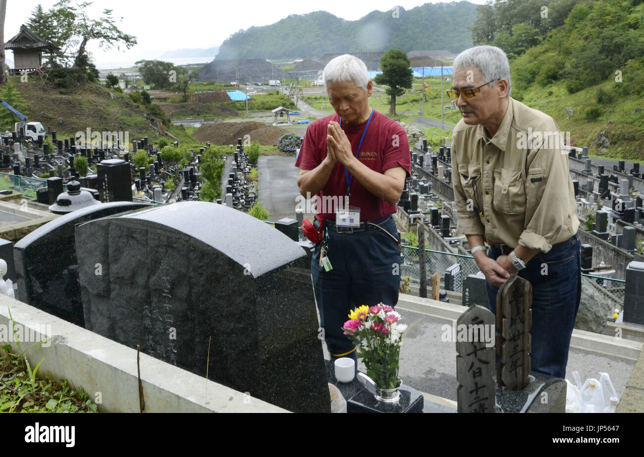 MORIOKA, Japón - Shuetsu Kubo (R), quien tiene una débil visión, visita la tumba de su hermano menor con la ayuda de personal voluntario en Kamaishi, Prefectura de Iwate, noreste de Japón, el 11 de julio de 2014. Kubo comenzaron a expresar su gratitud por su familia a través de la caligrafía tras perder a su hermano menor en el 2011 terremoto y maremoto. (Kyodo) Foto de stock