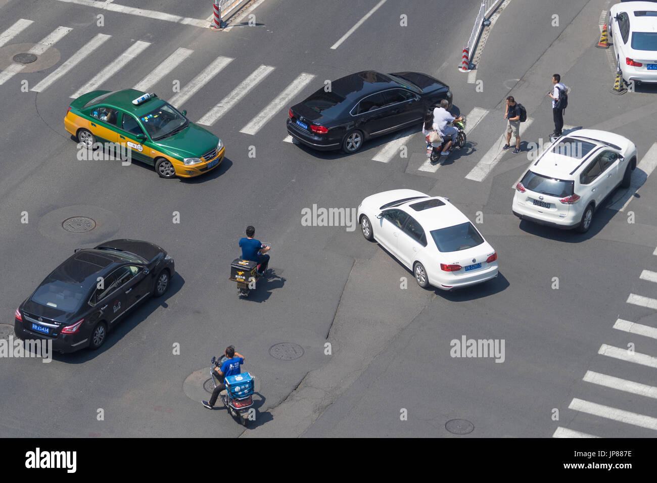 Típica calle Beijing caótico tráfico con automóviles, motocicletas y peatones todos convergen en amplio boulevard intersección Foto de stock