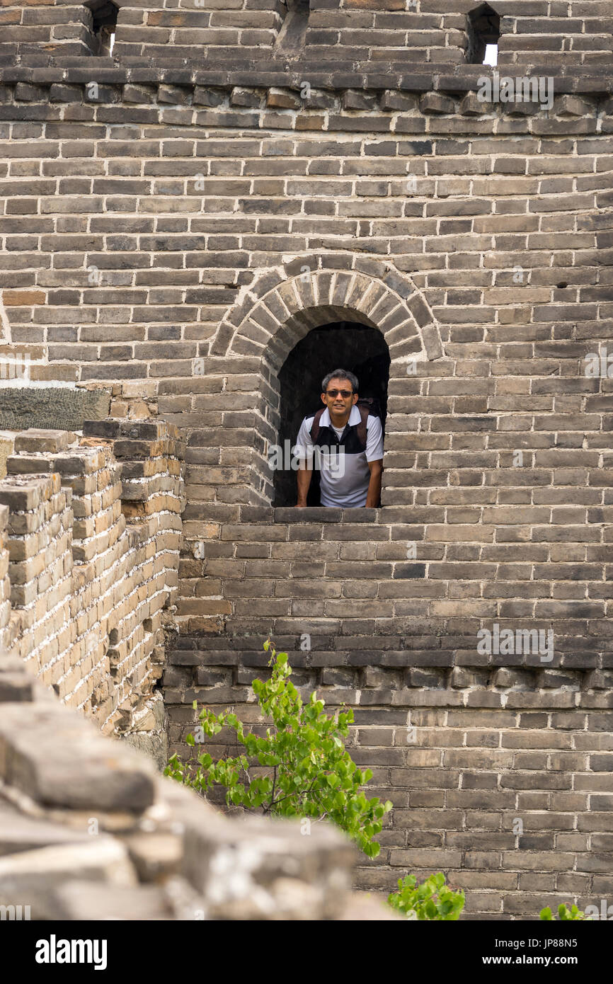 Turista indio en sus primeros 50s mirando desde la ventana arqueada en la Gran Muralla de China Foto de stock
