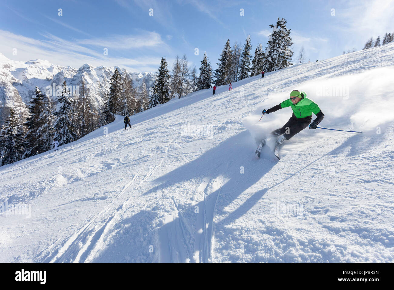 Un esquiador es a lo largo de las laderas de esquí en la estación de esquí Folgarida con Grupo Brenta en el fondo Foto de stock