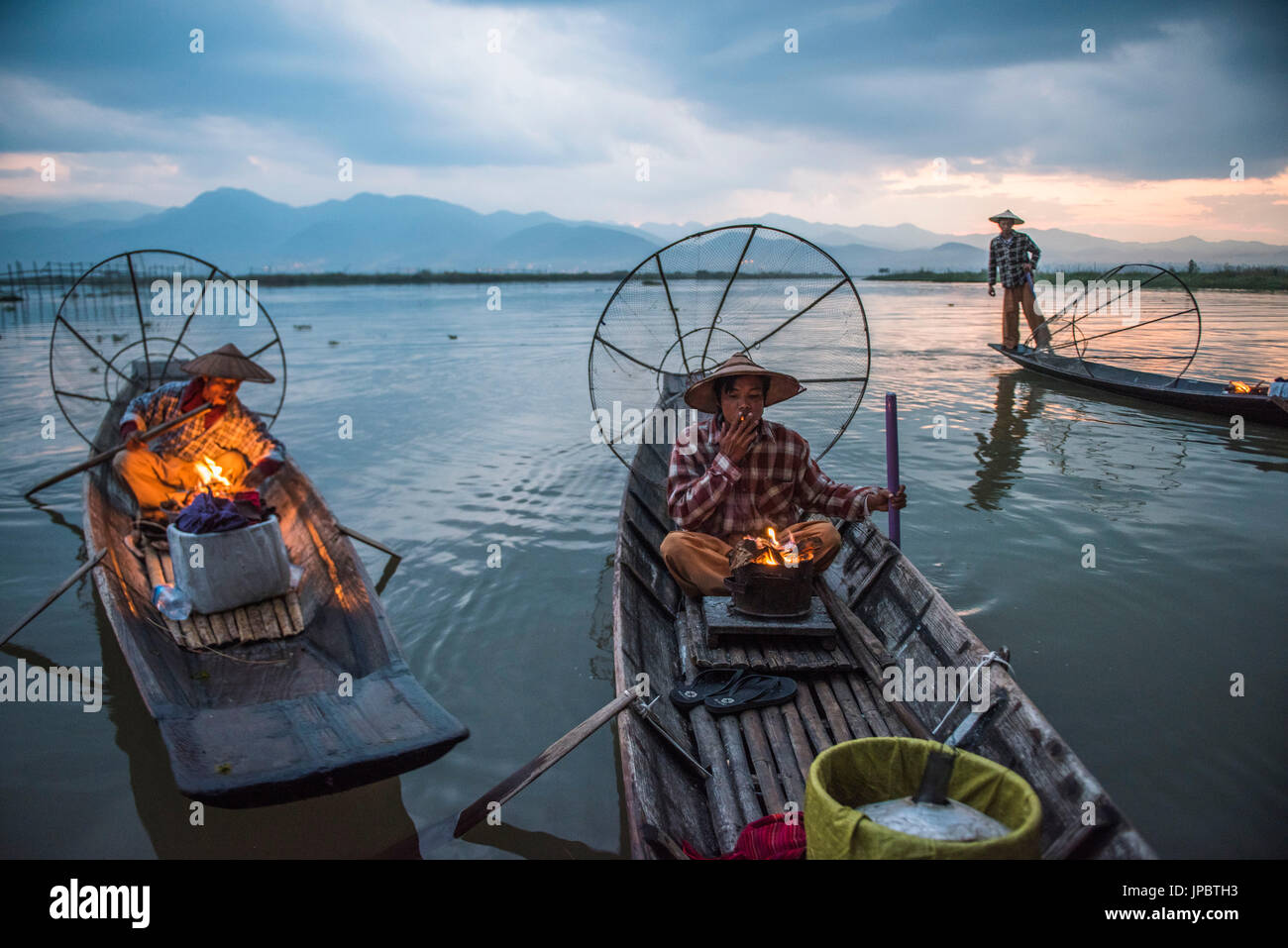 El lago Inle, Nyaungshwe township, distrito de Taunggyi, Myanmar (Birmania). Los pescadores locales antes del amanecer, con chimenea en el barco. Foto de stock
