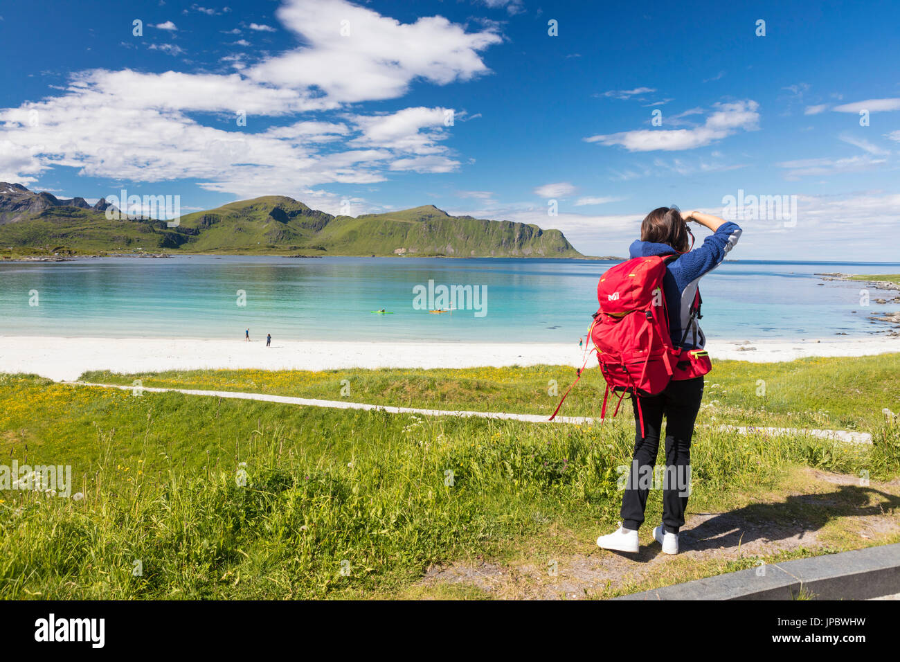 Fotógrafo en acción en las verdes praderas rodeadas de mar turquesa y arena fina Ramberg Islas Lofoten Noruega Europa Foto de stock