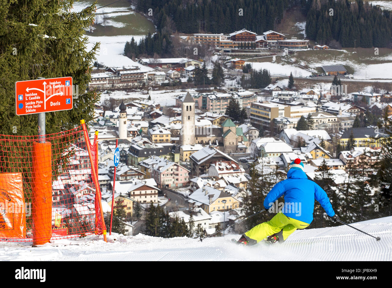Esquiador en las pistas de esquí, con la aldea alpina de San Cándido, en el fondo de Val Pusteria Dolomitas Bolzano Tirol del Sur Italia Europa Foto de stock
