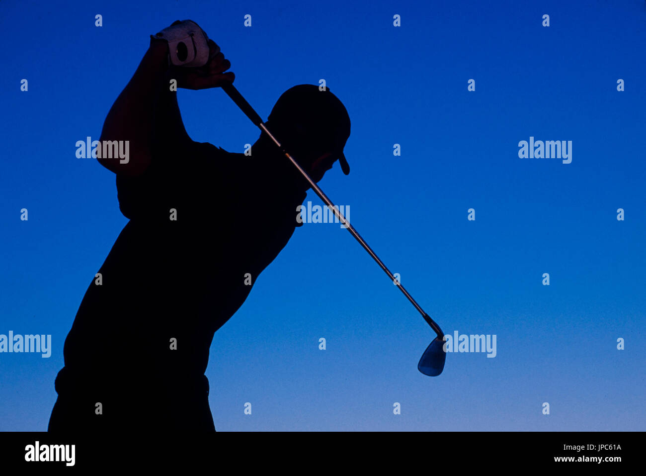 Un hombre es golfista siluetas contra un cielo azul profundo. Foto de stock