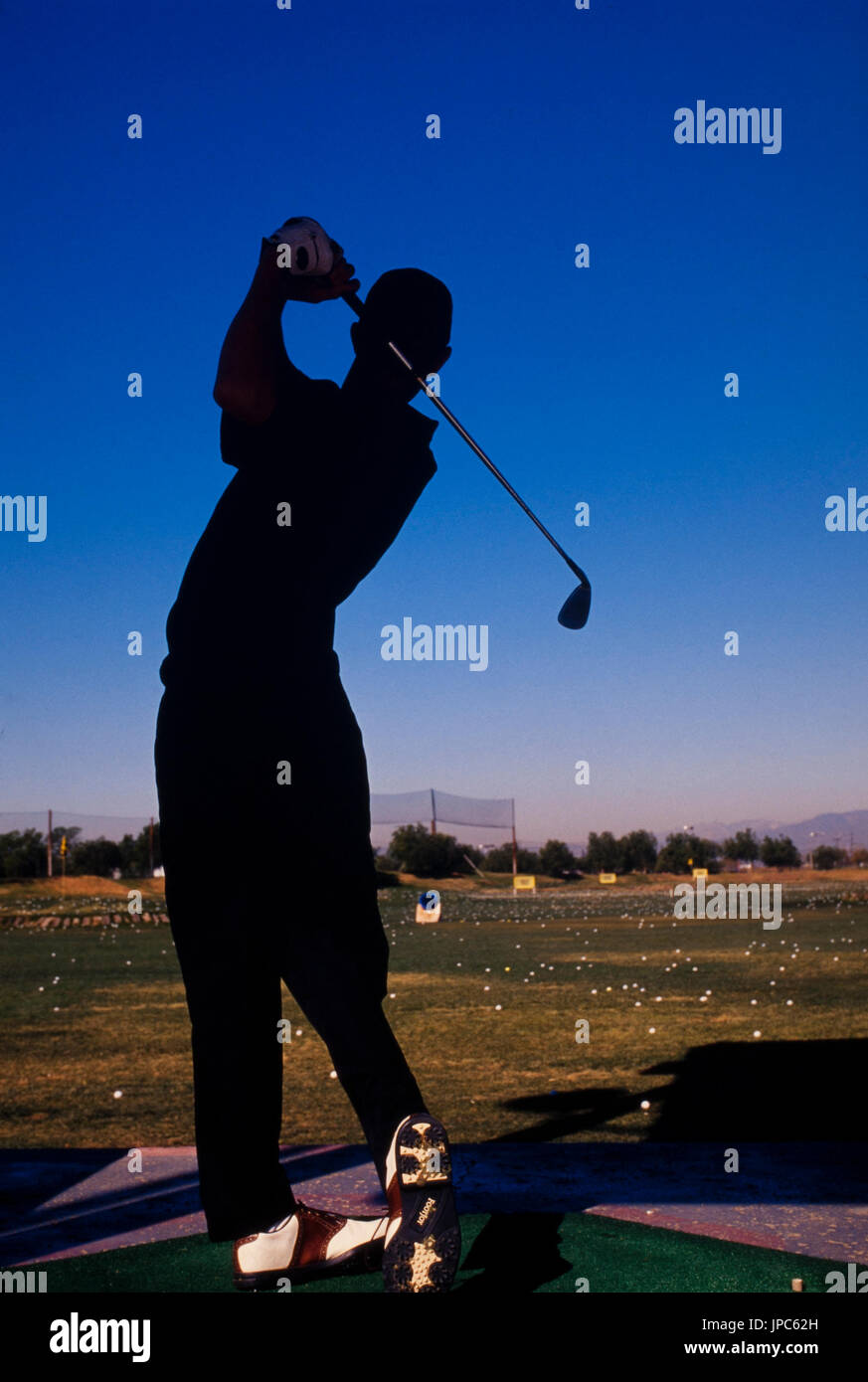 Un hombre es golfista siluetas contra un cielo azul profundo. Foto de stock