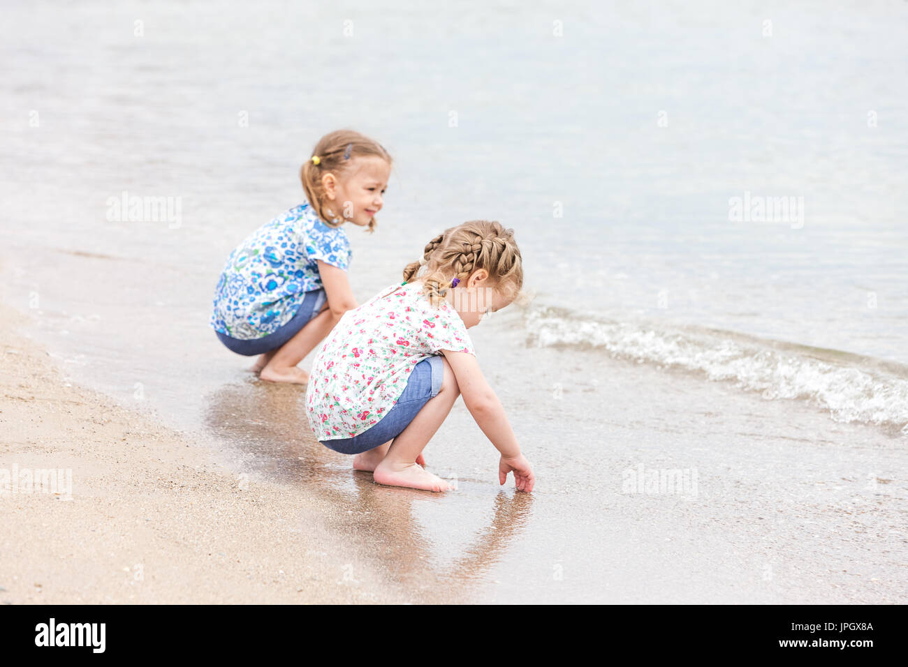 Niños en la playa. Gemelos sentado junto al agua de mar Fotografía de stock  - Alamy