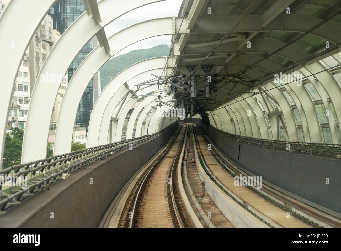 Las vías de ferrocarril de tránsito masivo en Hong Kong pasando bajo marco curvo y se dirigían hacia el centro de Hong Kong Foto de stock
