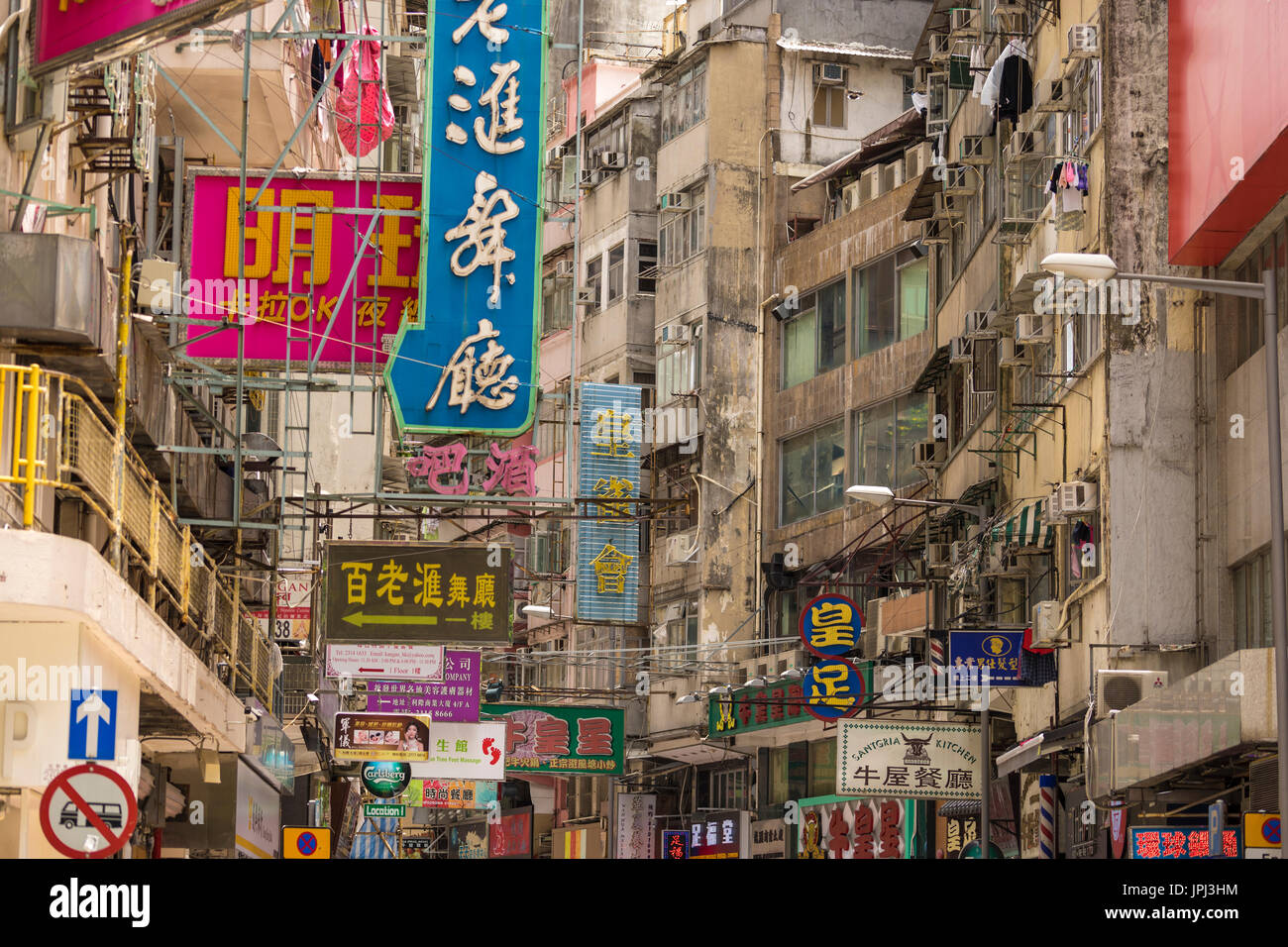 Cacofonía de chino e inglés signos en edificios ruinosos en la sección comercial de Kowloon, Hong Kong Foto de stock