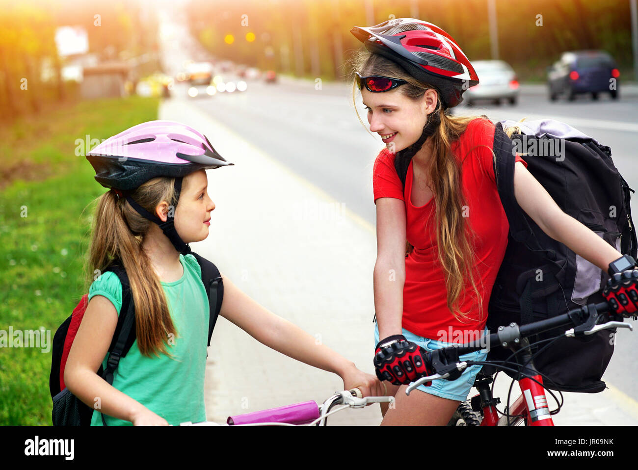 Bicicletas ciclista chica. Las niñas llevar casco de bicicleta y cristal  con mochila ciclyng bicicleta. Las niñas niños ciclismo en carril bici  amarilla. Tono de color Fotografía de stock - Alamy