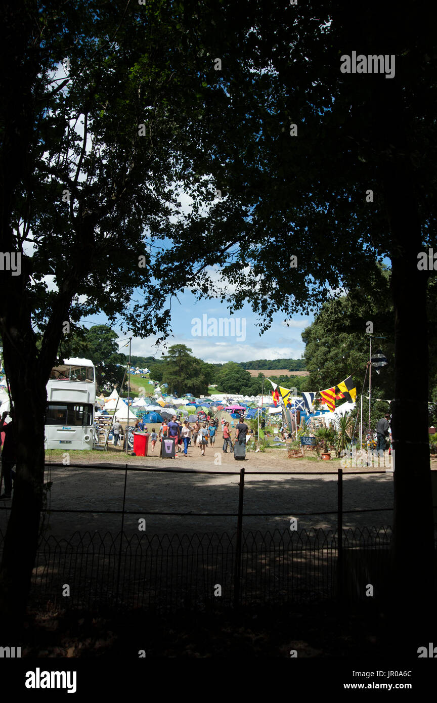 Una vista del camping y multitudes a través de los árboles en el puerto Eliot Festival en Cornualles, Reino Unido Foto de stock