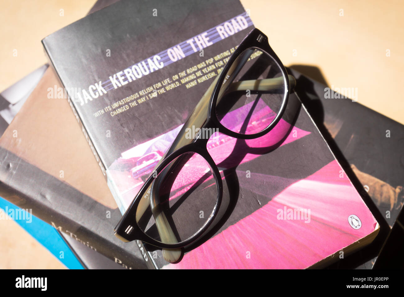 Gafas de lectura en la parte superior de una pila de libros con uno de ellos es la famosa novela de Jack Kerouac "en el camino" - concepto de lectura Foto de stock