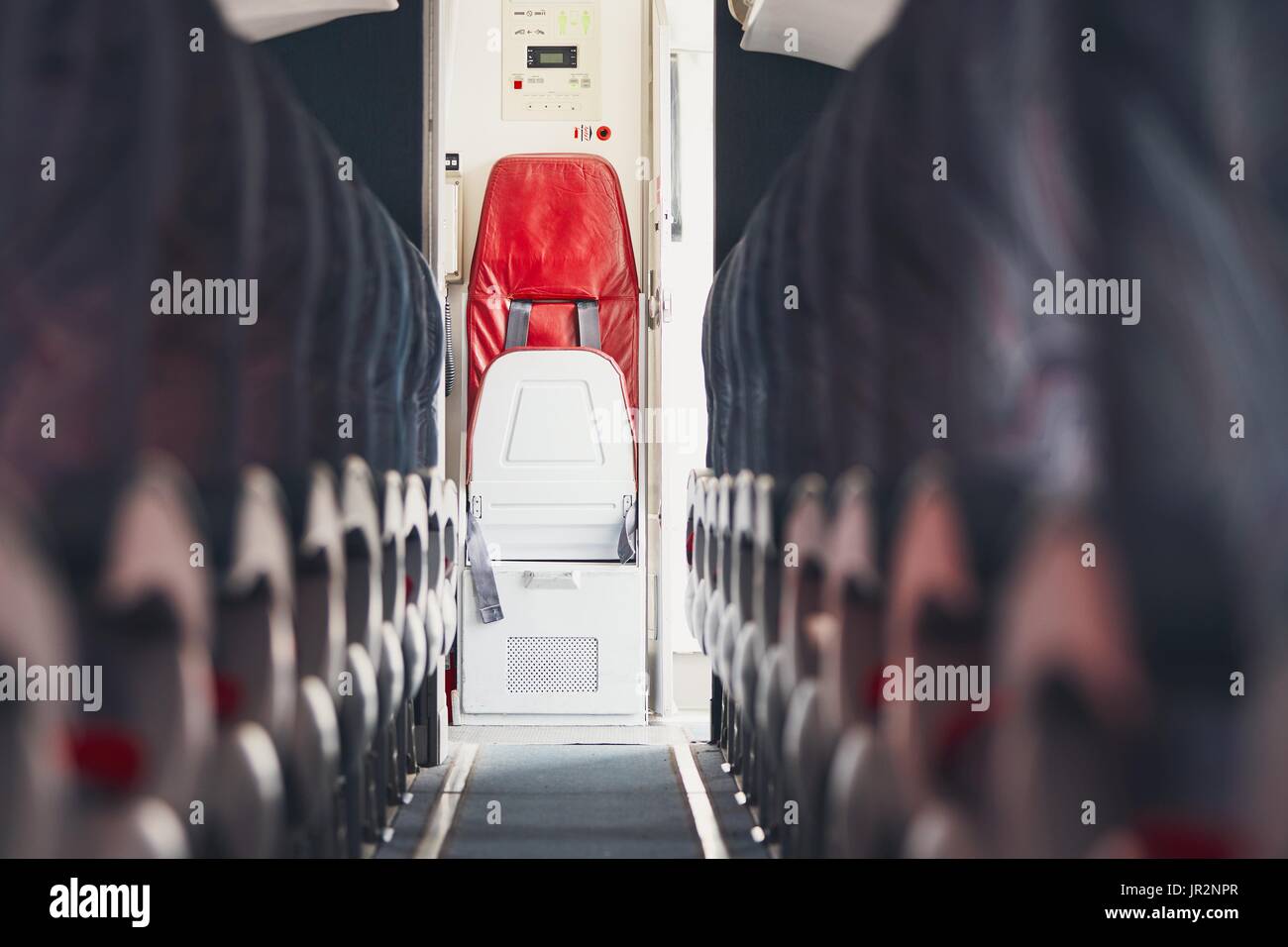 Pasillo en clase turista y asiento plegable para la tripulación de cabina en el avión comercial. Foto de stock