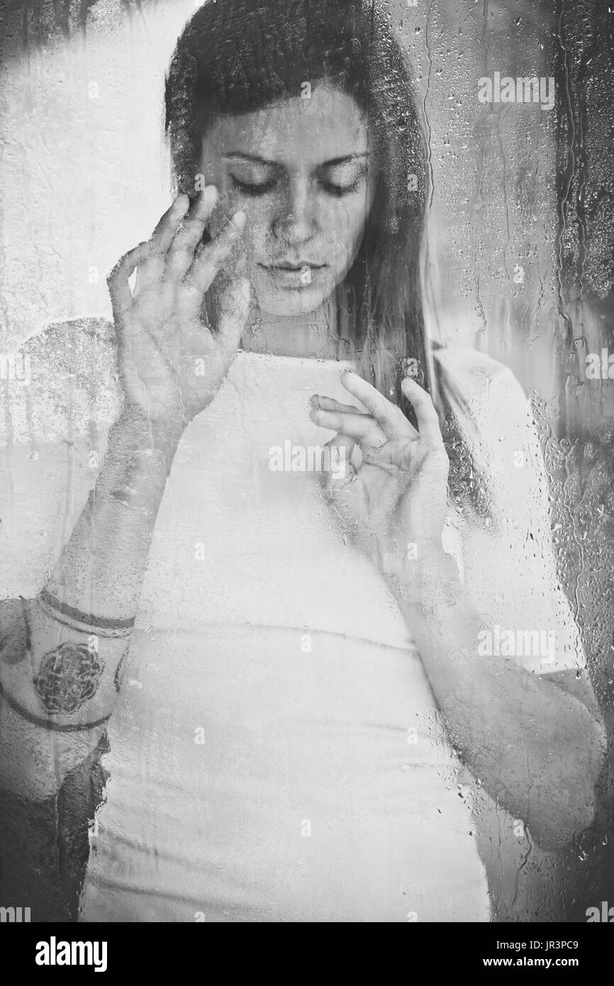 Mujer detrás de un vidrio mojado Foto de stock