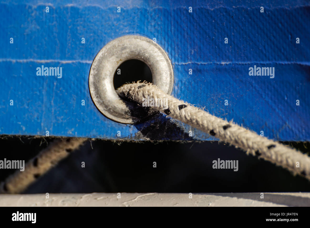 Ojales oxidado viejo sobre un anciano azul de plástico recubierto de lona para uso agrícola y temporalmente colgando en un Foto de stock
