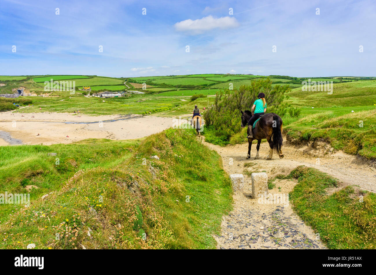 Montar a caballo en una playa del Reino Unido en la costa sur oeste de camino a la playa Gunwalloe, península de Lizard, Cornualles, en el Reino Unido en verano Foto de stock