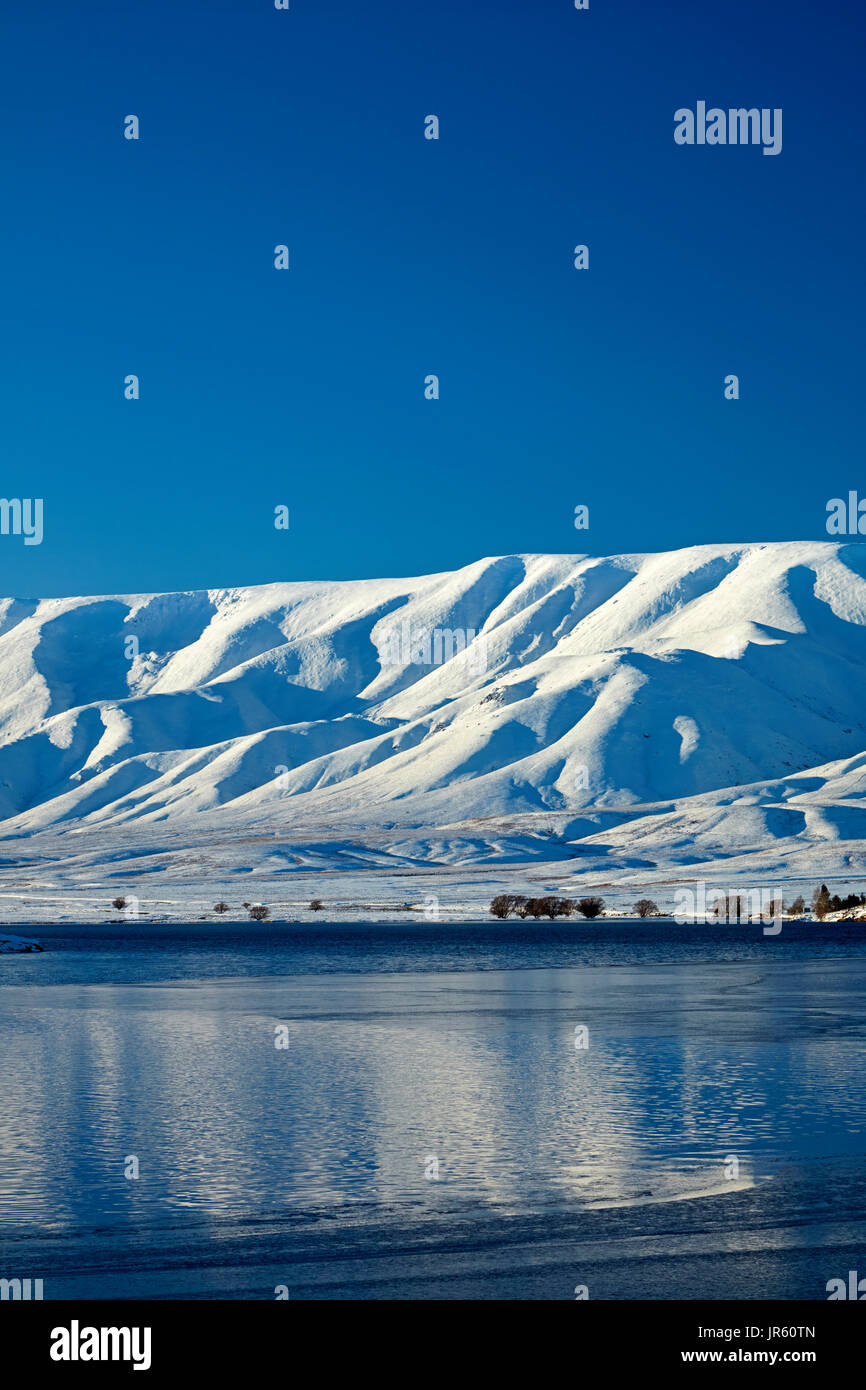 Falls Dam y gama Hawkdun en invierno, Maniototo, Central Otago, Isla del Sur, Nueva Zelanda Foto de stock