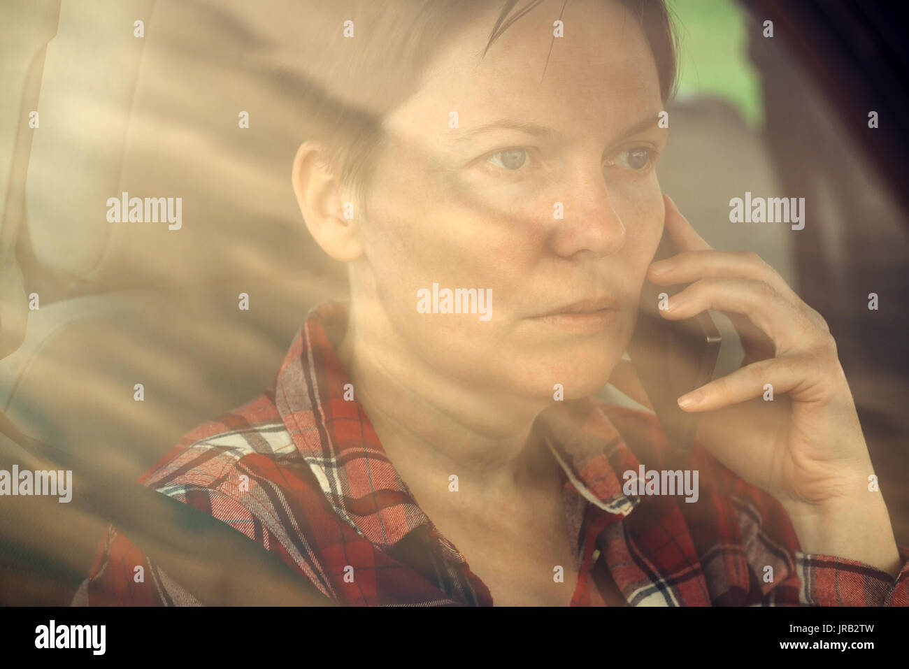 Preocupado mujer hablando por un teléfono móvil en el coche, interesados adulto hembra caucásica persona durante la conversación telefónica Foto de stock
