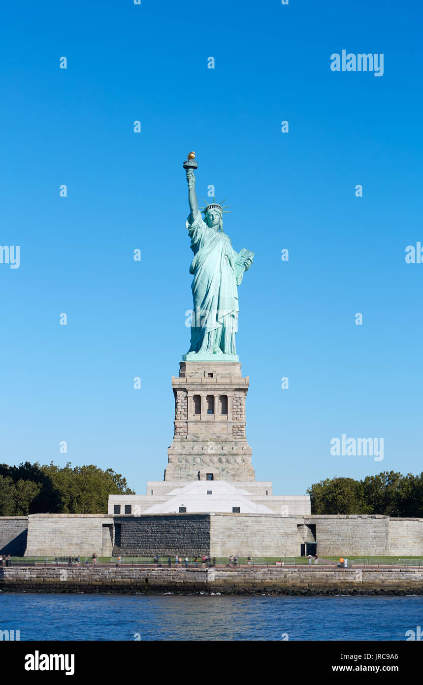 Estatua de la libertad con el pedestal y la Isla de la Libertad, en un día soleado, cielo azul en Nueva York Foto de stock