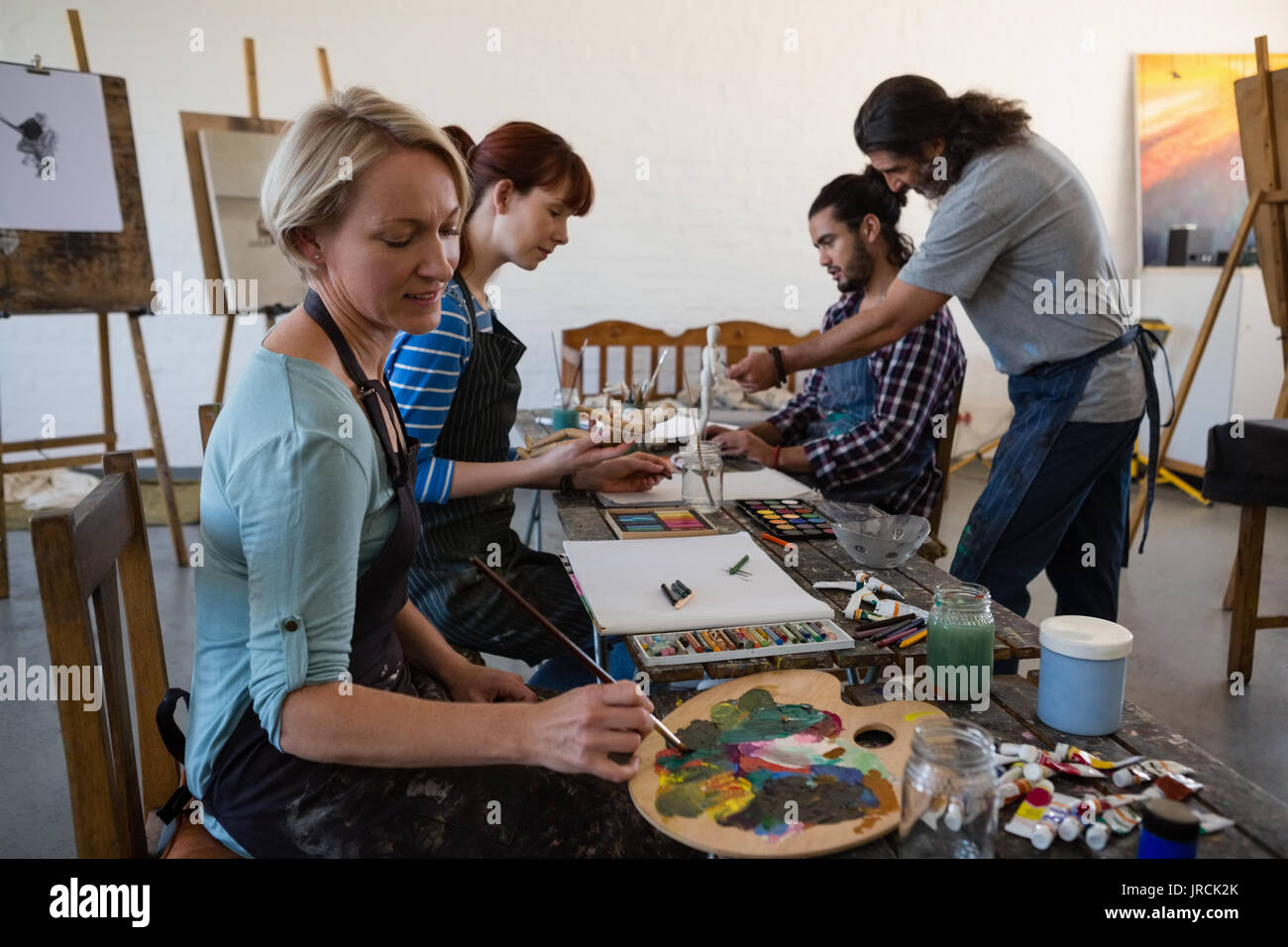 Profesor de pintura para orientar a los estudiantes en la clase de arte  Fotografía de stock - Alamy