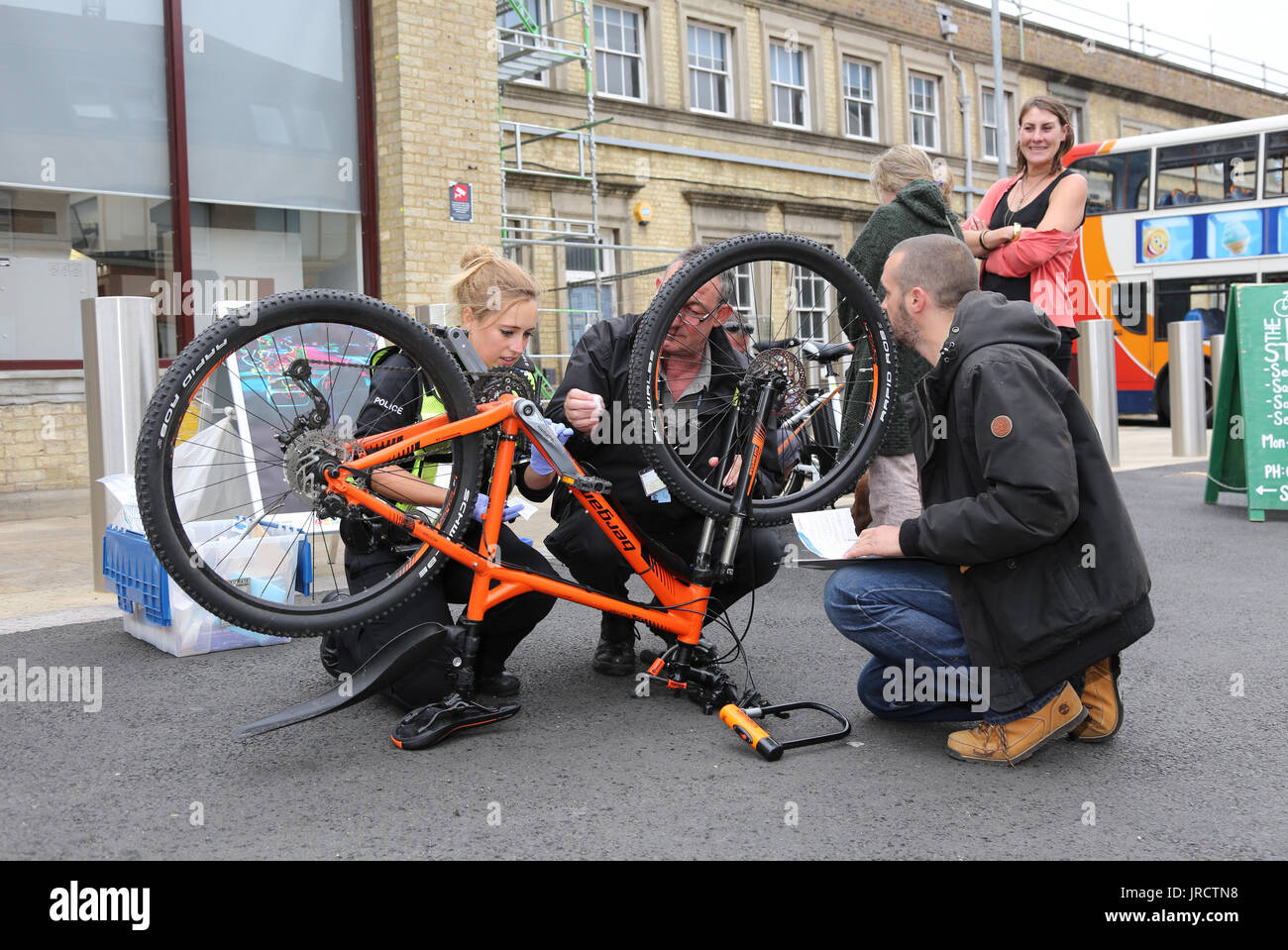 Un evento de registro de bicicletas en Cambridge, Reino Unido. Una mujer policía marcas de seguridad una bicicleta mientras que los detalles son grabadas por un colega. Foto de stock