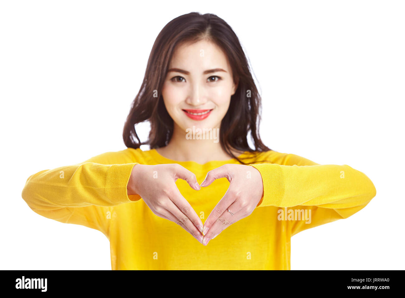 Joven y bella mujer asiática mostrando una forma corazón formado con sus manos, aislado sobre fondo blanco. Foto de stock