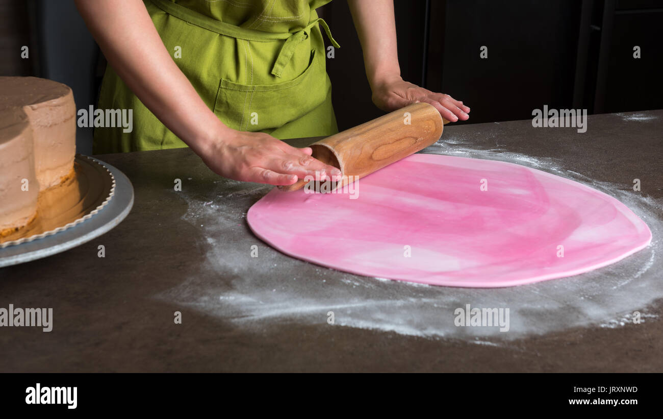 Mujer utilizando el pasador rodante preparando rosa para decorar tortas de  fondant o masa elastica, manos detalle Fotografía de stock - Alamy