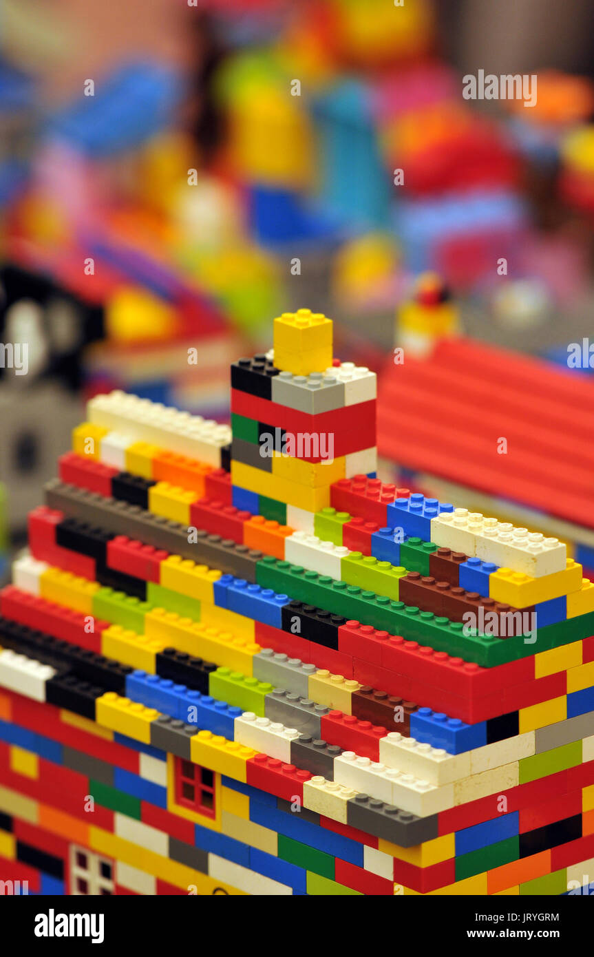 Varias piezas de Lego de colores brillantes junto a una construcción Lego.  los juguetes para niños y juegos de construcción para construir el  aprendizaje de construcción y arquitectura Fotografía de stock -