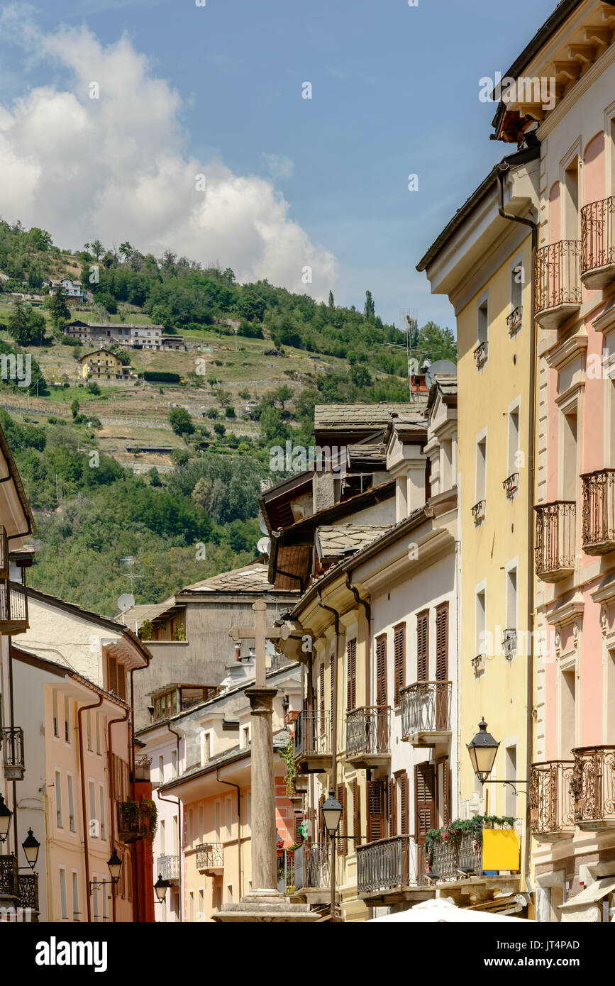 Fachadas de casas antiguas con la pendiente de la montaña se cierne sobre antecedentes, rodada en un brillante día de verano en Aosta, Italia Foto de stock
