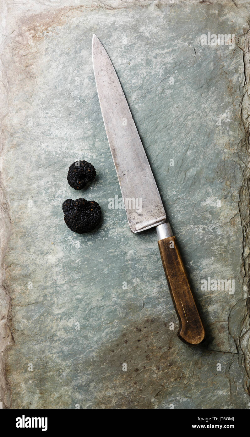 La trufa negra y el cuchillo de cocina en piedra pizarra esquisto antecedentes Foto de stock