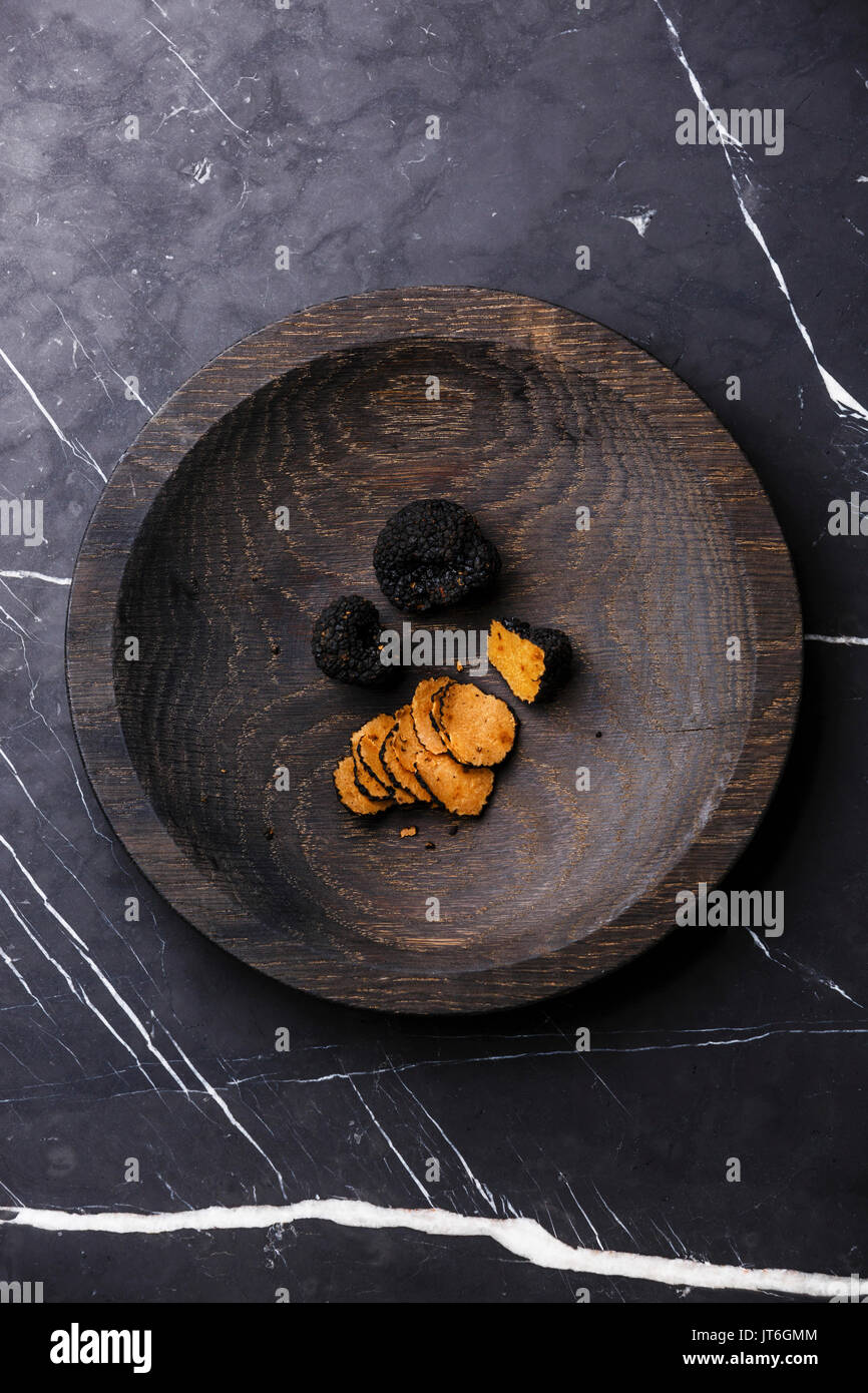 Placa de madera en la trufa negra sobre fondo de mármol oscuro Foto de stock