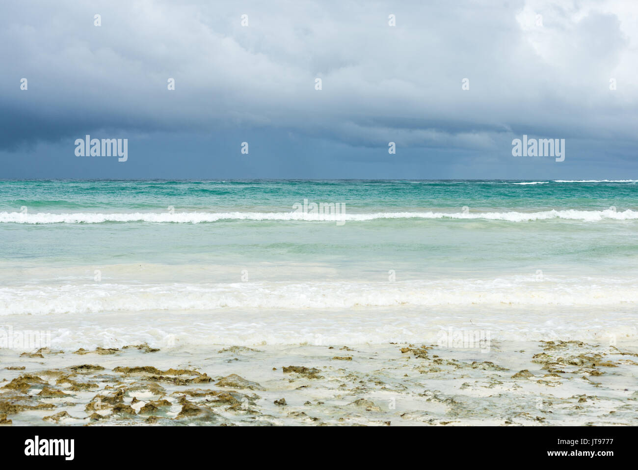 Nube de lluvia en el horizonte, con el océano Índico y la costa de playa en primer plano, Diani, Kenya Foto de stock