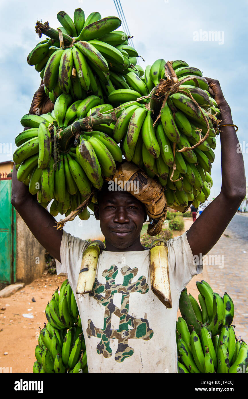 El hombre lleva un montón de plátanos en su cabeza, Bujumbura, Burundi, África Foto de stock