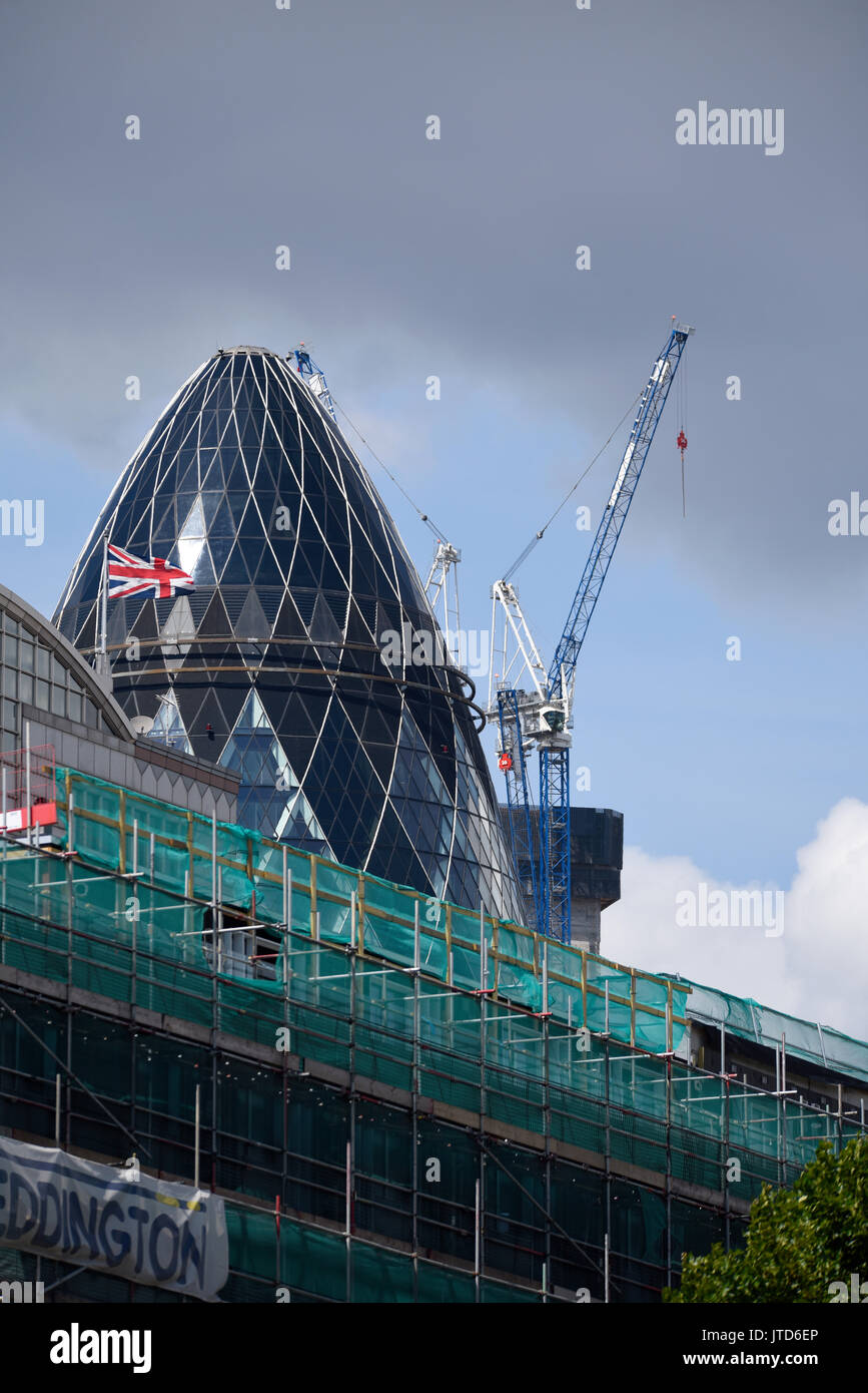 Calle comercial sitio en construcción en frente del pepinillo 30 St Mary Axe de Londres, Reino Unido. Bandera Union Jack y grúas torre. Espacio para copiar Foto de stock