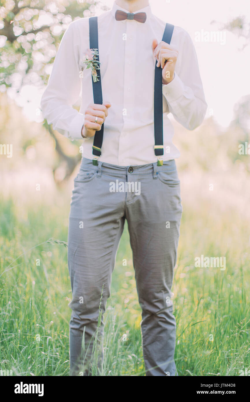 Outlook Themodern del novio en el pantalón gris, camisa blanca, tirantes  con la flor de mariposa de madera y accesorios en el fondo del bosque de  primavera Fotografía de stock - Alamy