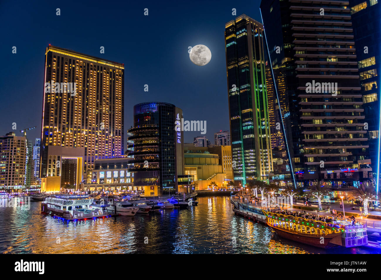 Vista del puerto deportivo de Dubai en la noche con una gran luna, Dubai, Emiratos Árabes Unidos. Foto de stock